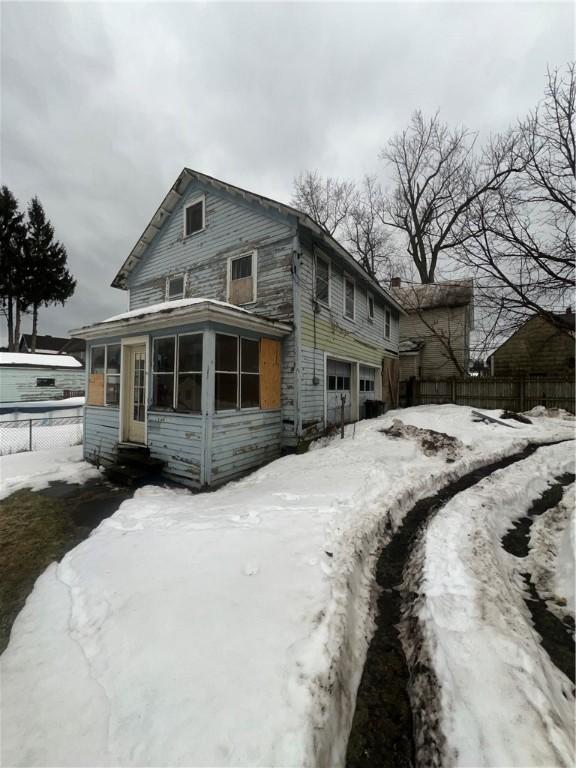 view of front of house featuring a sunroom, fence, and an attached garage