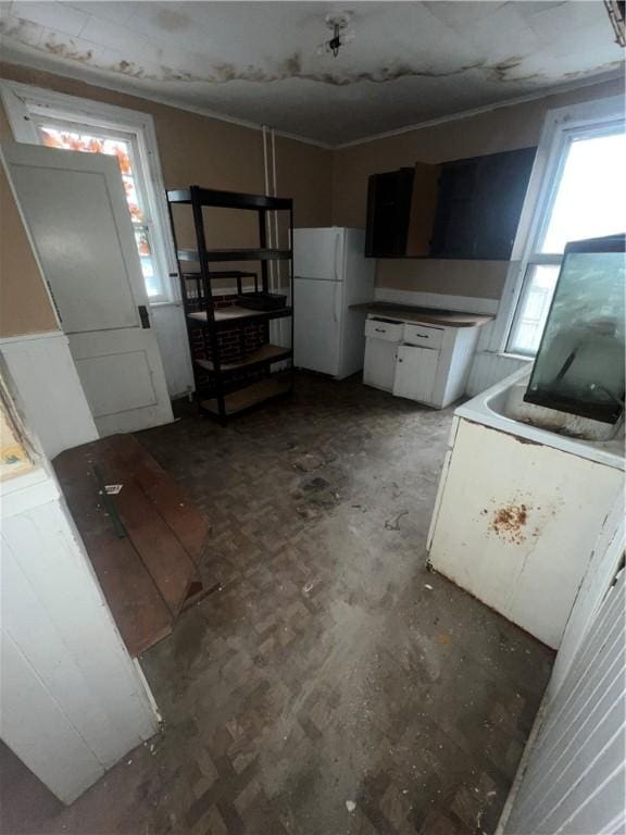 kitchen with freestanding refrigerator and white cabinetry