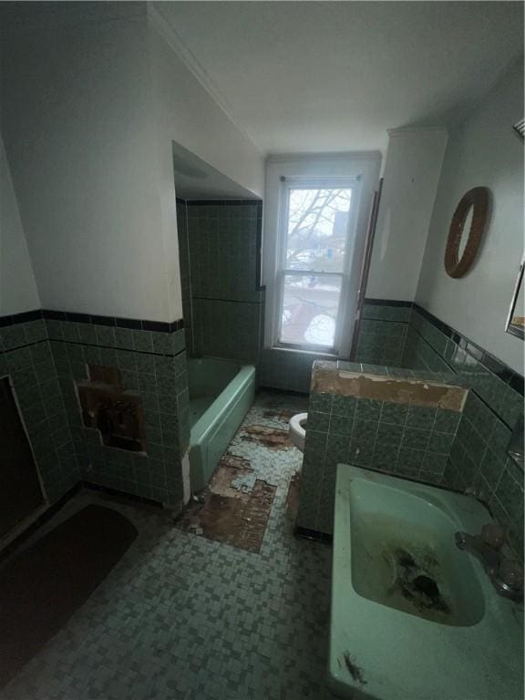 full bath featuring a tub to relax in, a wainscoted wall, tile walls, and toilet