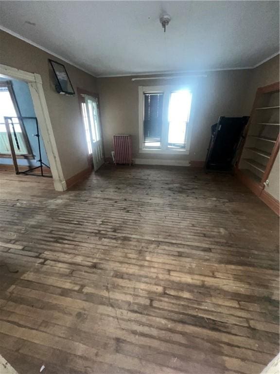 interior space featuring ornamental molding, baseboards, radiator heating unit, and wood finished floors