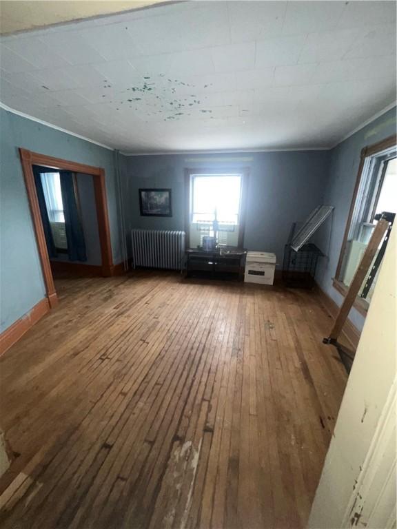 interior space with baseboards, ornamental molding, wood-type flooring, and radiator