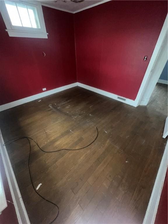 spare room featuring dark wood-style floors, visible vents, and baseboards