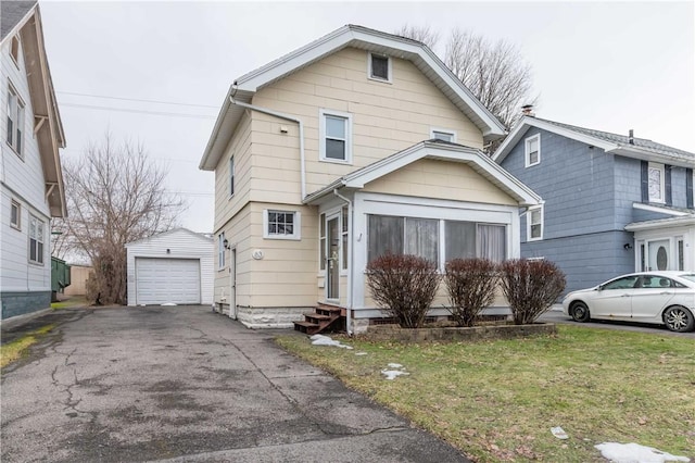 view of front of property featuring entry steps, an outdoor structure, a detached garage, driveway, and a front lawn