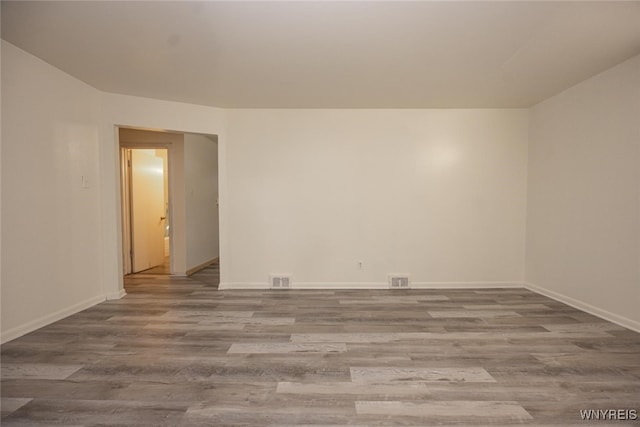 spare room with visible vents, baseboards, and wood finished floors