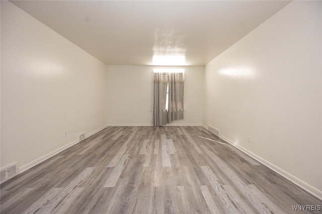 spare room with baseboards, visible vents, and wood finished floors