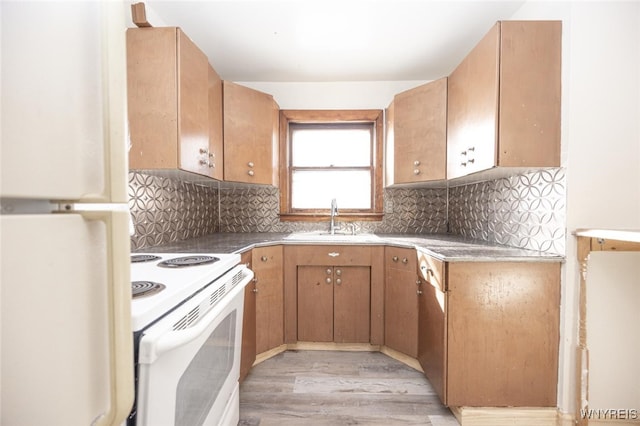 kitchen featuring tasteful backsplash, white appliances, a sink, and light wood finished floors