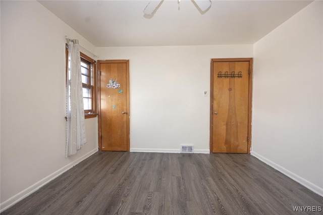 unfurnished room featuring ceiling fan, dark wood-type flooring, visible vents, and baseboards