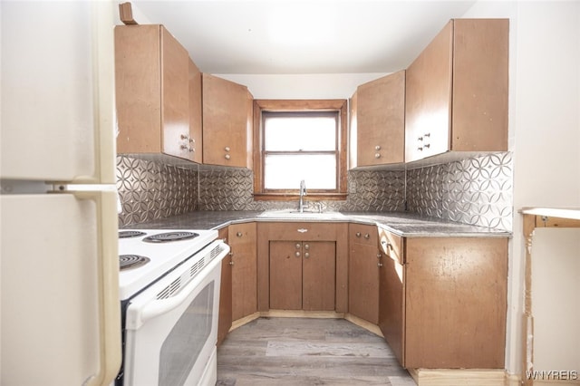 kitchen featuring light wood-type flooring, white appliances, backsplash, and a sink