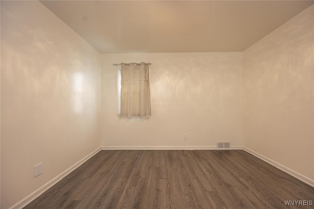 empty room with visible vents, baseboards, and dark wood-type flooring