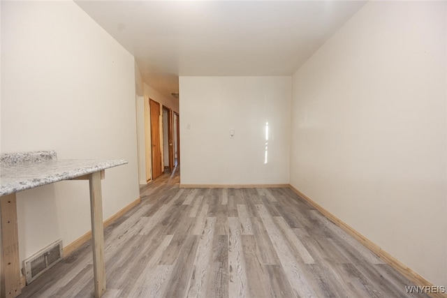 empty room with light wood-style floors, visible vents, and baseboards