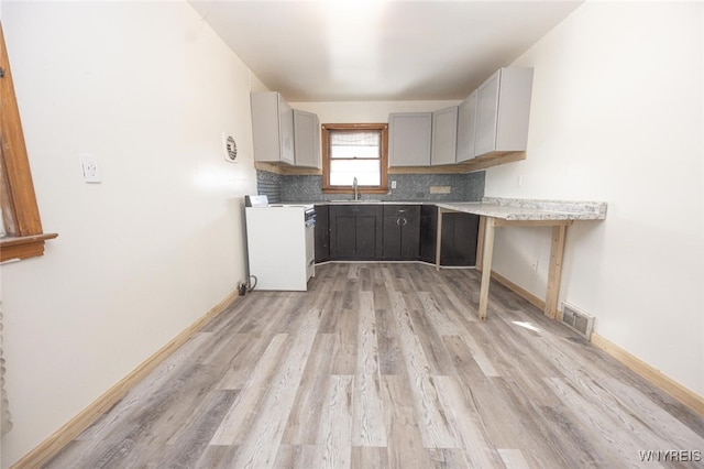 kitchen with range, gray cabinets, light countertops, decorative backsplash, and a sink