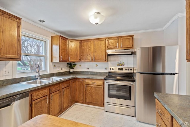 kitchen with under cabinet range hood, a sink, appliances with stainless steel finishes, backsplash, and brown cabinetry