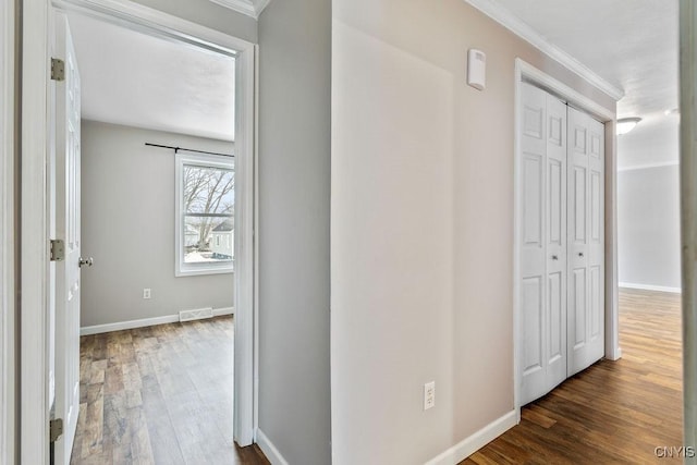 hall featuring visible vents, baseboards, and wood finished floors