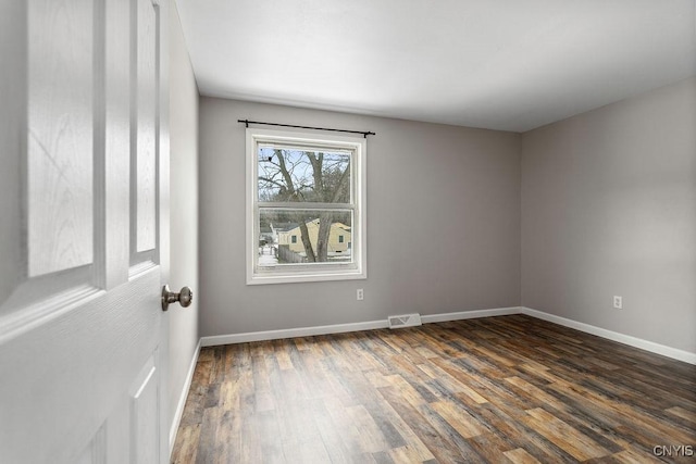 unfurnished room with dark wood finished floors, visible vents, and baseboards