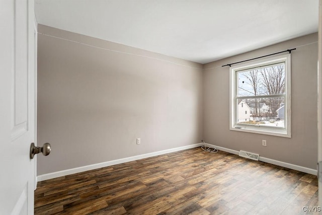 unfurnished room with wood finished floors, visible vents, and baseboards