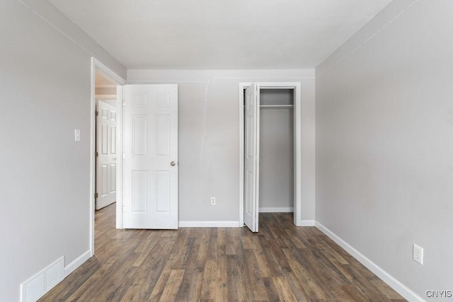 unfurnished bedroom featuring baseboards, a closet, visible vents, and wood finished floors