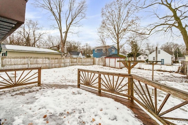 yard covered in snow with a fenced backyard, a residential view, and a wooden deck