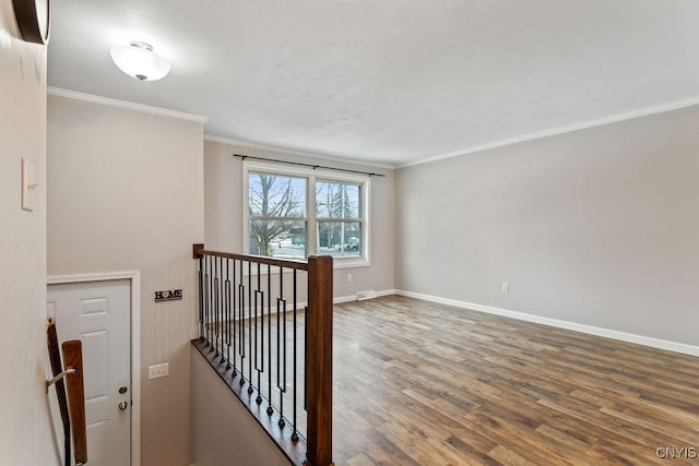 interior space featuring crown molding, baseboards, and wood finished floors