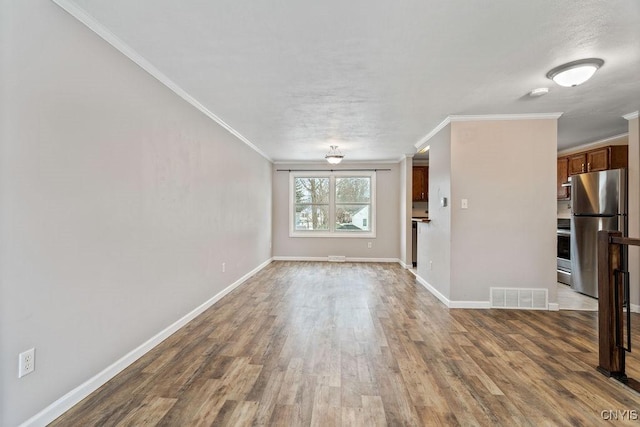 unfurnished living room with ornamental molding, wood finished floors, visible vents, and baseboards