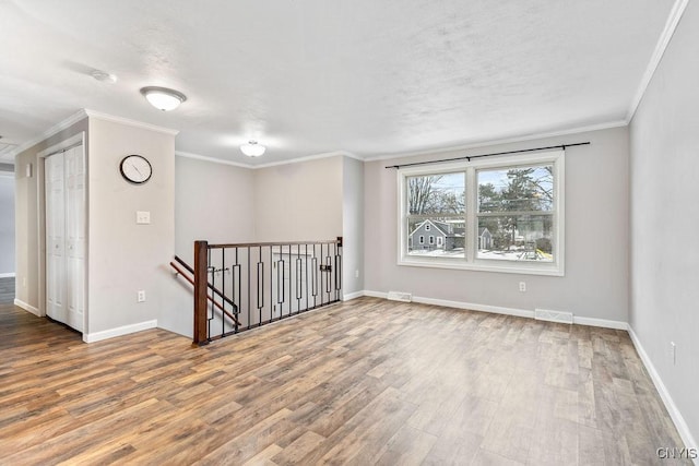 unfurnished room with visible vents, crown molding, baseboards, and wood finished floors