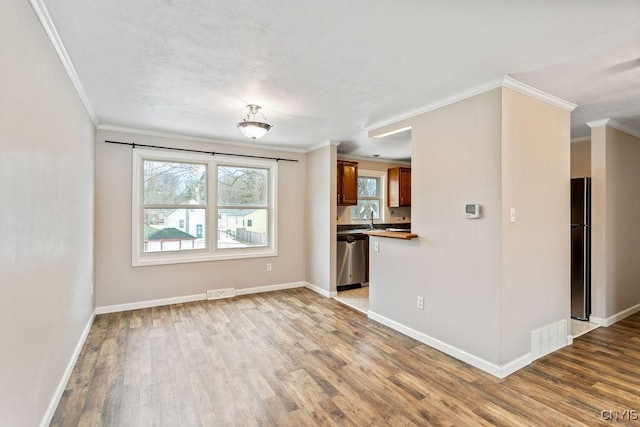 unfurnished living room with ornamental molding, wood finished floors, visible vents, and baseboards