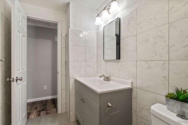 bathroom with toilet, tile walls, and vanity