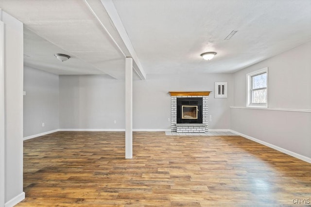 unfurnished living room featuring a fireplace, wood finished floors, and baseboards