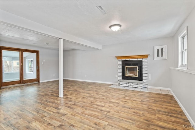 unfurnished living room featuring a fireplace, visible vents, a wealth of natural light, and wood finished floors