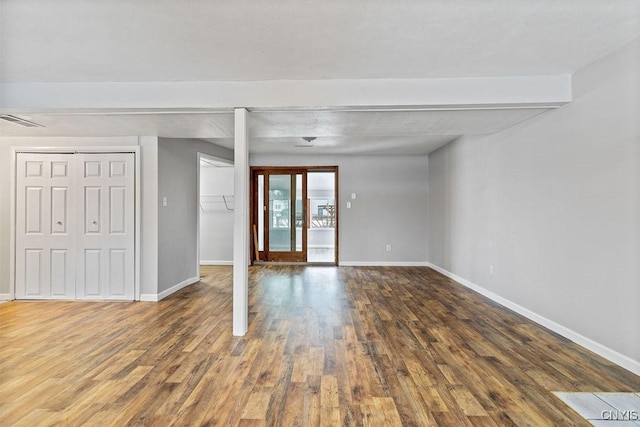 empty room with wood finished floors, visible vents, and baseboards