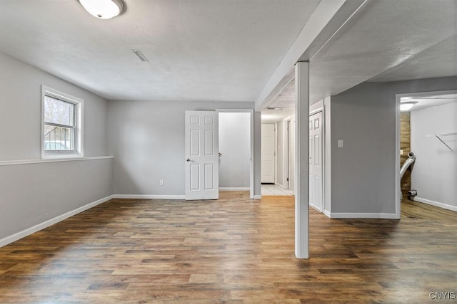 basement with visible vents, baseboards, and wood finished floors