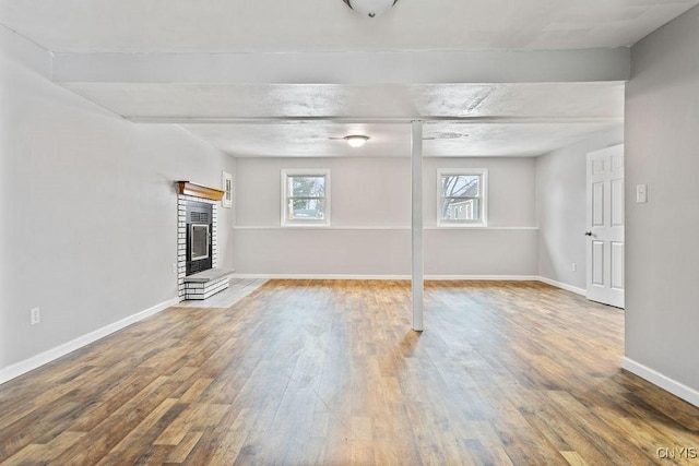 basement featuring a fireplace, baseboards, and wood finished floors