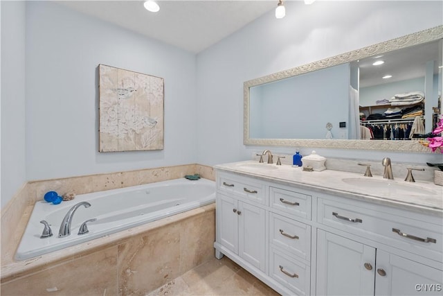 full bathroom with a garden tub, a spacious closet, double vanity, and a sink