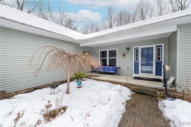 snow covered property entrance with covered porch