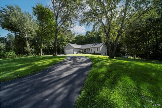 view of front of property featuring an attached garage, aphalt driveway, and a front yard