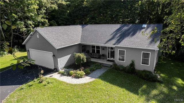 view of front of property with roof with shingles, a porch, an attached garage, driveway, and a front lawn