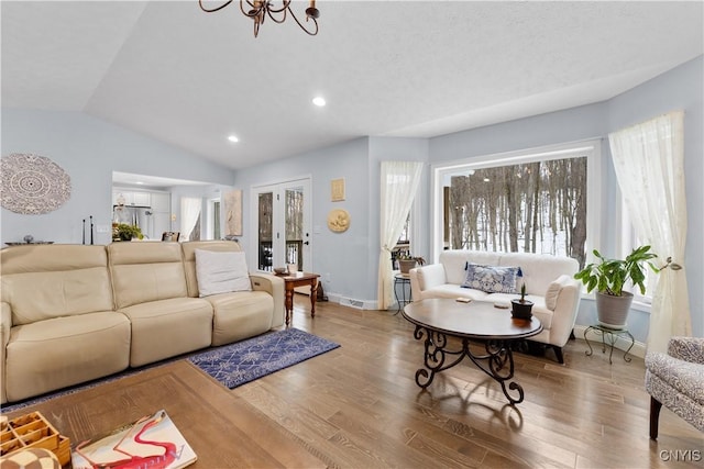 living area with lofted ceiling, a notable chandelier, recessed lighting, wood finished floors, and baseboards