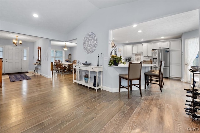 interior space with a peninsula, light wood-style floors, a kitchen bar, and stainless steel refrigerator with ice dispenser