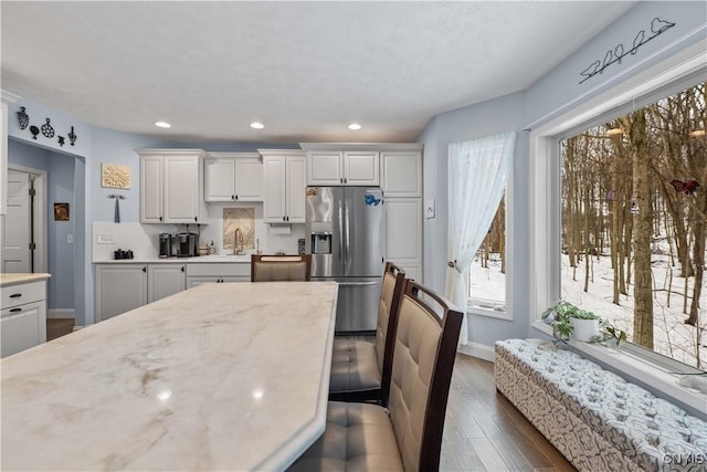 kitchen with baseboards, white cabinets, dark wood finished floors, stainless steel refrigerator with ice dispenser, and recessed lighting