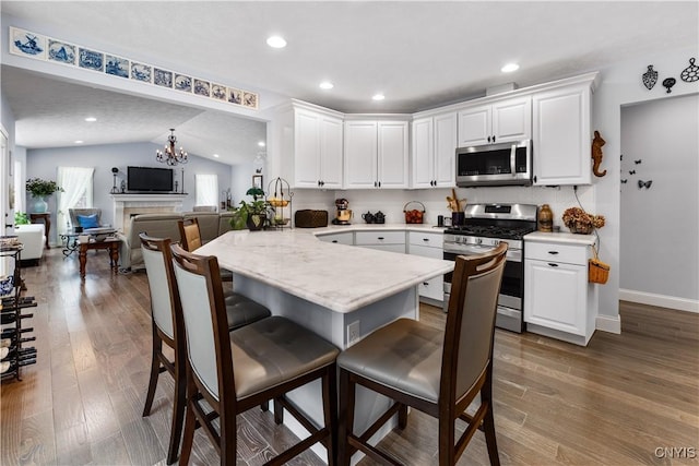 kitchen featuring stainless steel appliances, a breakfast bar area, light countertops, and white cabinets