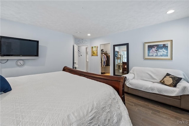 bedroom featuring a textured ceiling, a spacious closet, wood finished floors, and recessed lighting