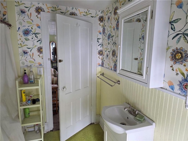 bathroom featuring wainscoting, vanity, and wallpapered walls