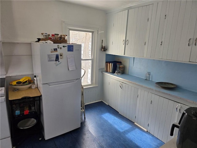 kitchen with freestanding refrigerator, light countertops, plenty of natural light, and white cabinetry