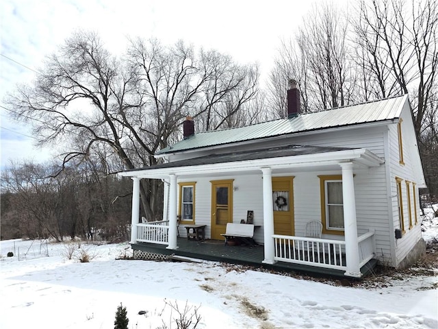 view of front of house with metal roof, a chimney, and a porch