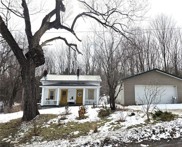 view of front of house featuring a garage, a chimney, metal roof, an outdoor structure, and a porch