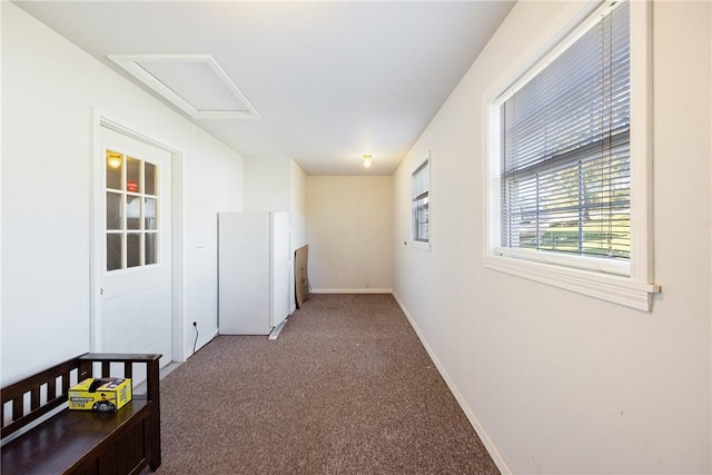 unfurnished room featuring attic access, carpet flooring, and baseboards