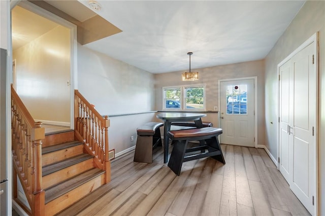 dining space featuring stairway, a chandelier, light wood-style flooring, and baseboards