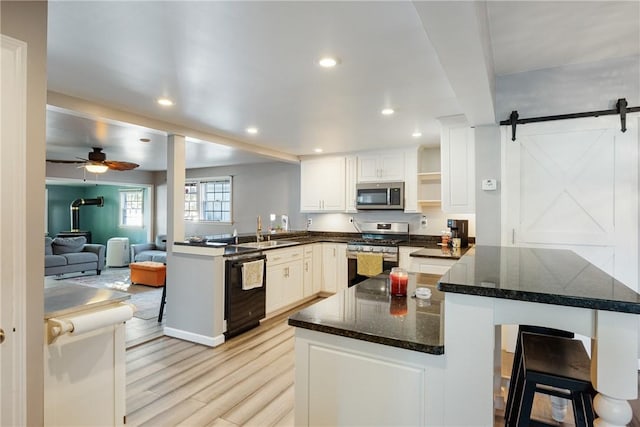 kitchen featuring stainless steel appliances, a barn door, a peninsula, and a sink