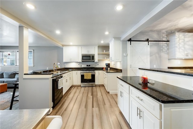 kitchen featuring a barn door, recessed lighting, appliances with stainless steel finishes, open shelves, and light wood finished floors