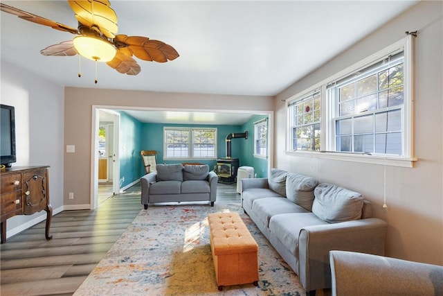 living area with a wood stove, a healthy amount of sunlight, baseboards, and wood finished floors