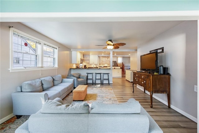 living room featuring ceiling fan, baseboards, and wood finished floors